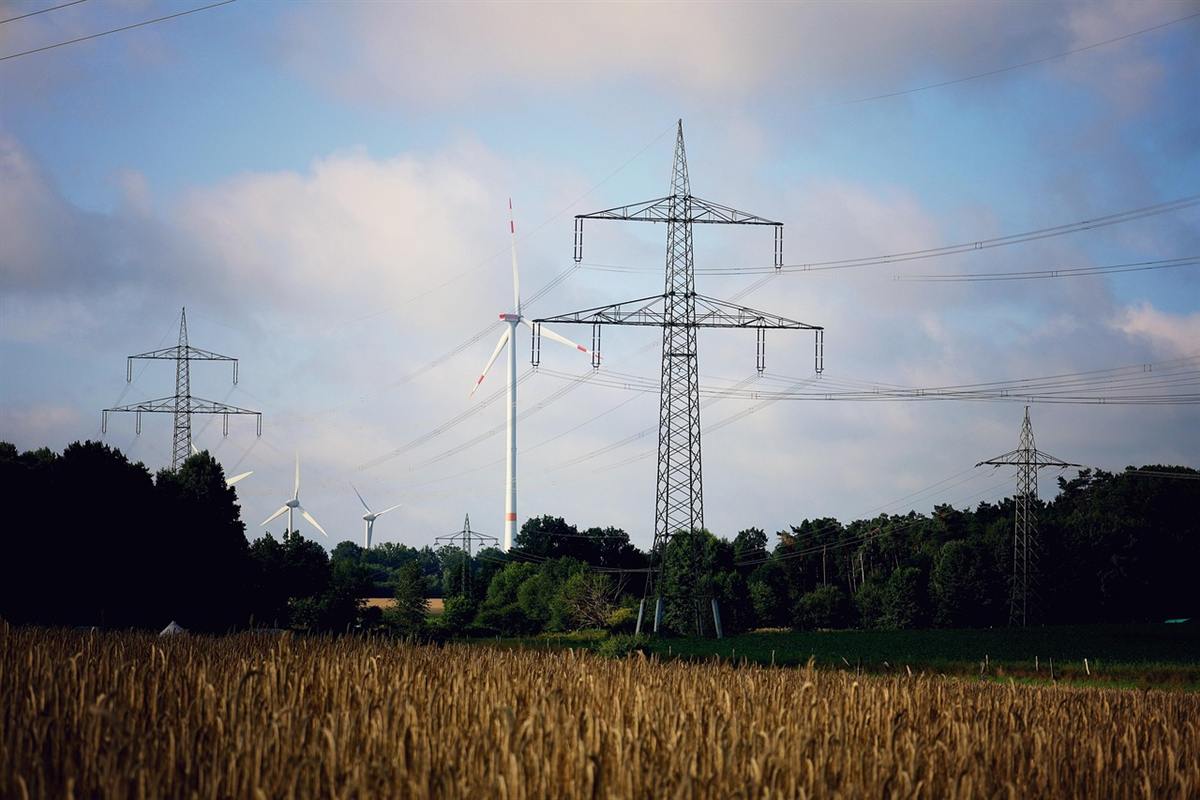Electricity pylons and wind turbines over farmland